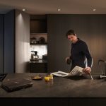man reading a newspaper in a kitchen that features blum revego pocket doors in the background