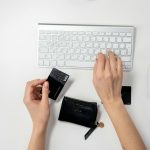 hands typing on a keyboard while holding a credit card